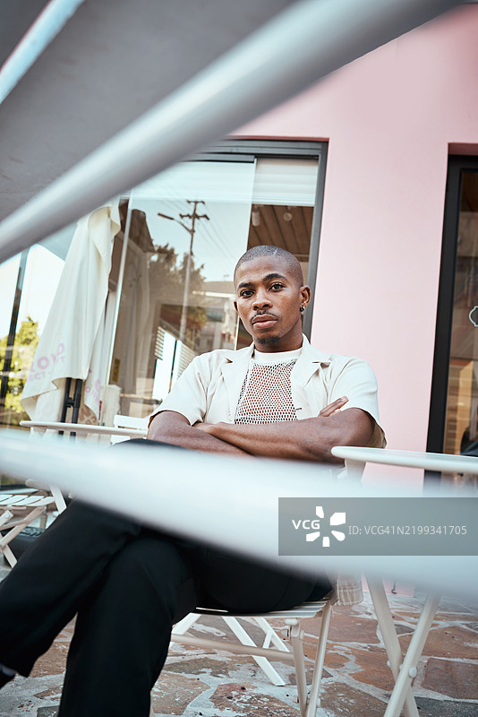 坐在现代咖啡馆外的男人，神情沉思，艺术栏杆环绕。图片素材