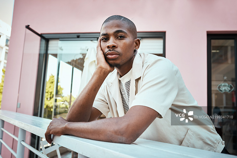 时尚年轻男子在阳光明媚的日子里，悠闲地在现代建筑附近放松。图片素材