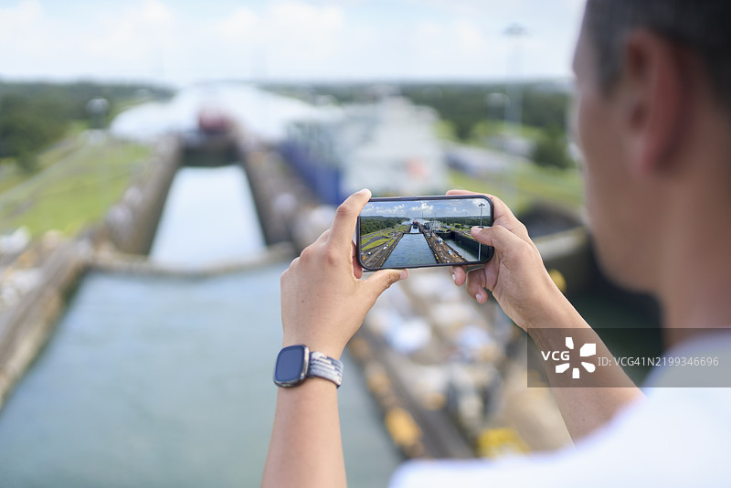 一名男子用智能手机拍摄巴拿马运河的特写镜头图片素材