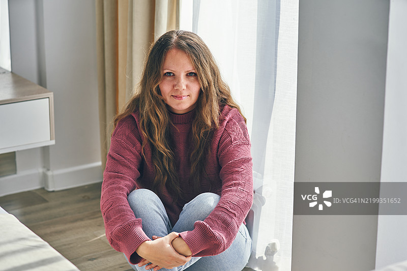 坐在阳光明媚的窗边，思考的女性在温馨的家居环境中图片素材