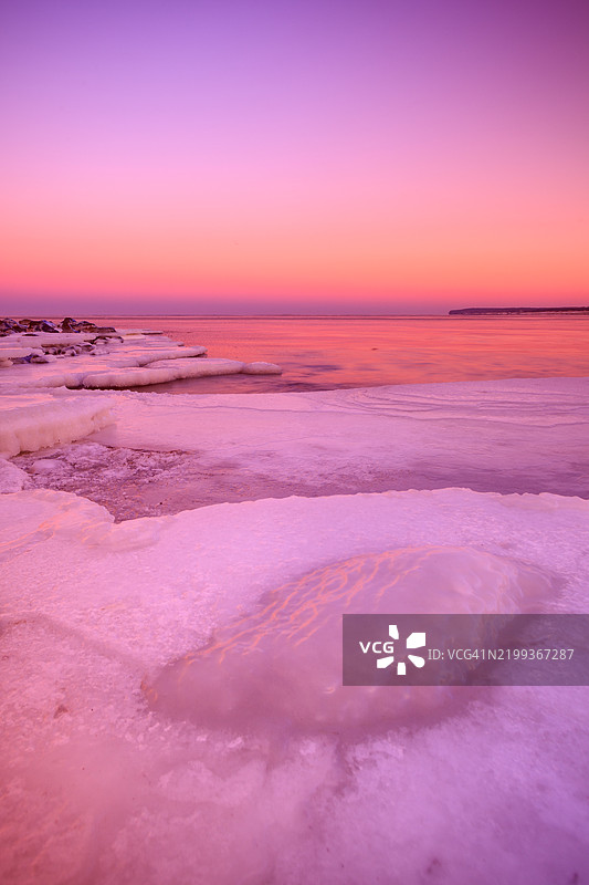 立陶宛克莱佩达冰冻岩石海岸上的粉色日落图片素材