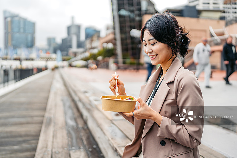 年轻的亚洲女商人在澳大利亚悉尼达令港的码头上吃沙拉图片素材