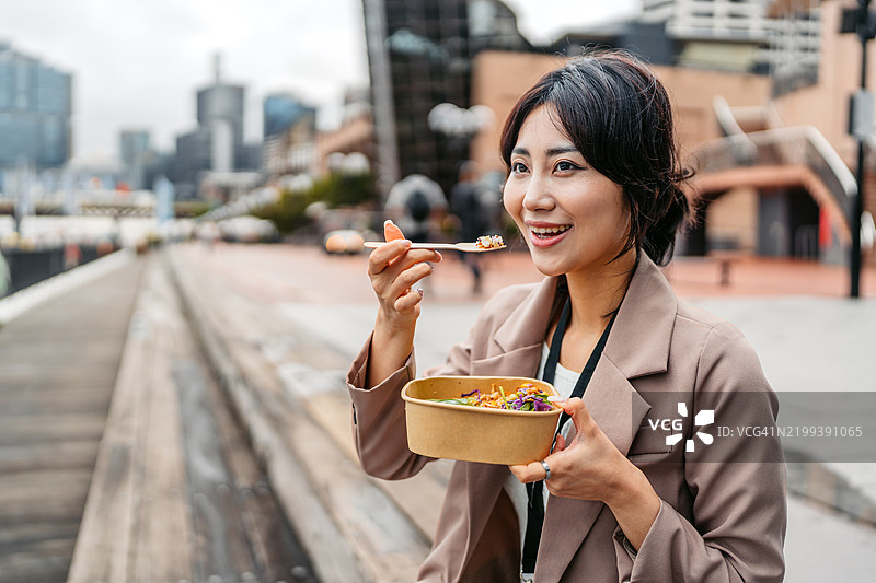 年轻的亚洲女商人在澳大利亚悉尼达令港的码头上吃沙拉图片素材