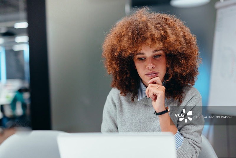 专注的年轻女商人在现代办公室使用笔记本电脑工作图片素材