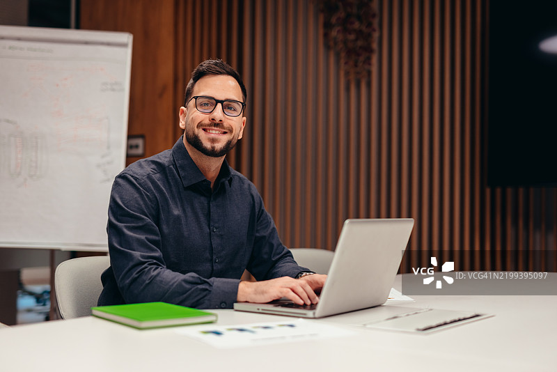 在现代办公室里工作的商人，面带微笑看向镜头图片素材