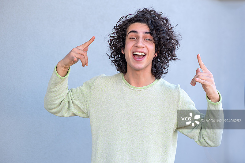 快乐的年轻人，卷发，指向上方。图片素材