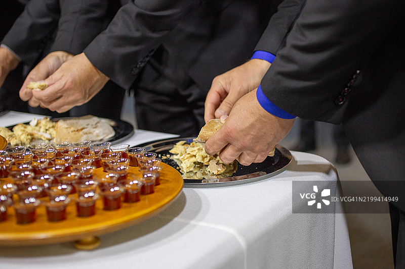 牧师的手在进行圣餐时撕开面包。图片素材