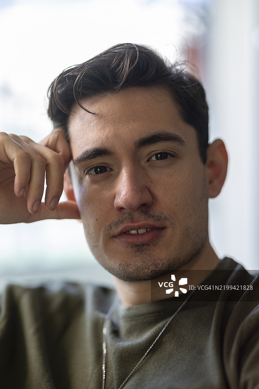 一个沉思的年轻男子，手放在头上图片素材