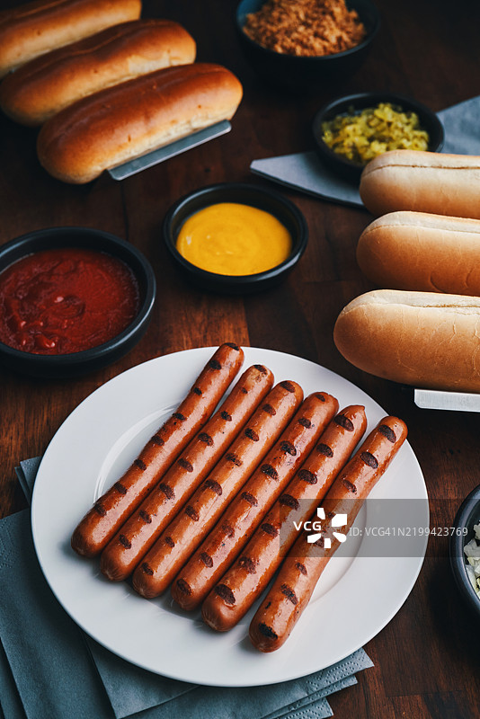 准备热狗，配烤洋葱、腌黄瓜酱、芥末和番茄酱图片素材