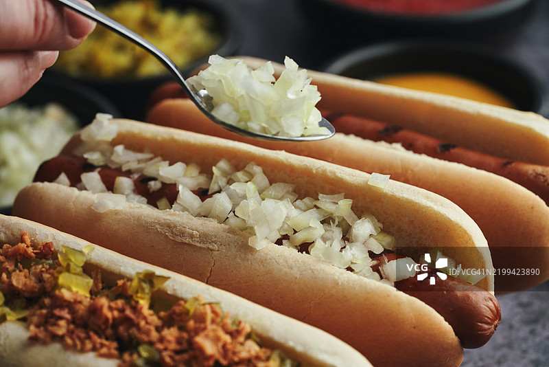 热狗的多种变化，配有烤洋葱、泡菜酱、芥末、番茄酱和各种配料图片素材