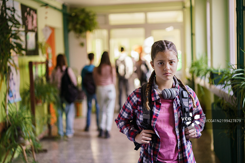 背着书包的伤心女孩肖像在学校里图片素材