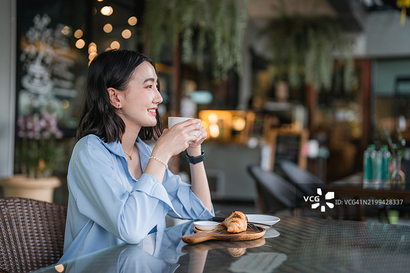 亚洲女性在咖啡店享受咖啡的肖像图片素材