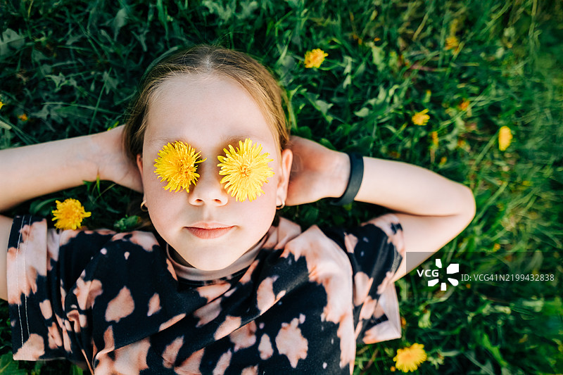 孩子在草地上放松，蒲公英遮住了眼睛图片素材