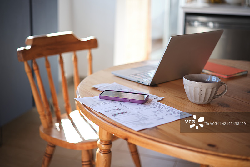 家庭预算规划。桌上有笔记本电脑、智能手机和水电费账单，周围没有人。管理你的财务。图片素材