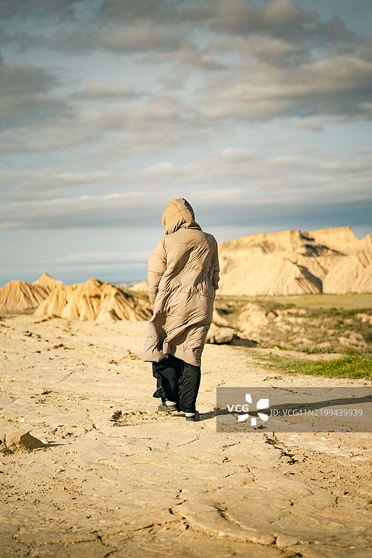 年轻女性穿着厚外套，沉思并欣赏巴尔德纳斯·雷亚莱斯沙漠的岩石 formations，旅行世界的概念。图片素材