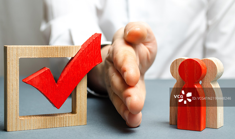 一名男子用手掌和红色勾选标记将一群人分开，象征着防止候选人选举的概念，口袋中的反对派和控制选举，破坏民主价值观。图片素材