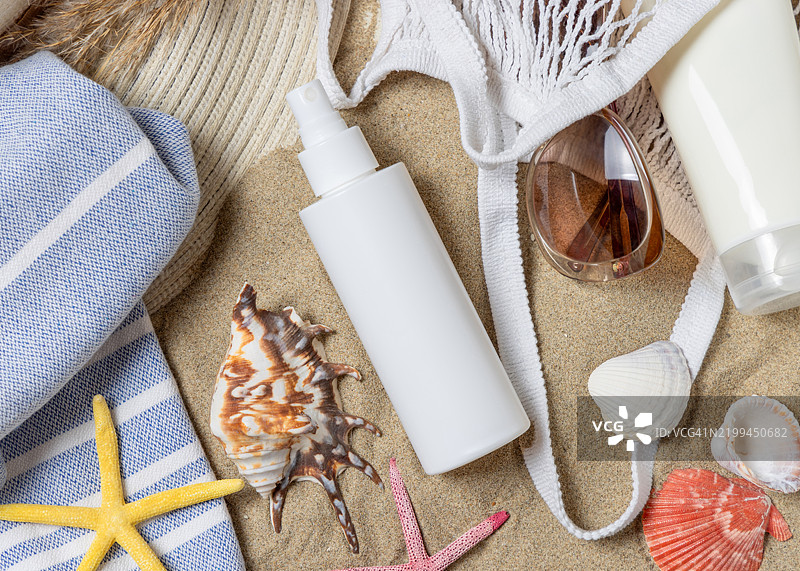 防晒喷雾瓶、太阳镜、毛巾、沙滩上的海星和贝壳、化妆品样品图片素材