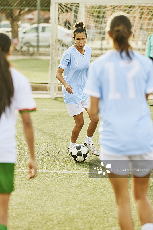 宽镜头女性足球运动员在比赛中带球向前推进图片素材
