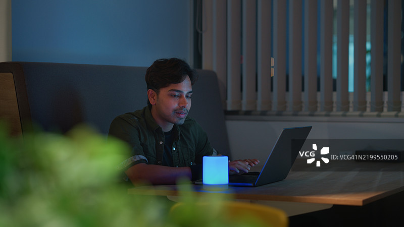 年轻多元化的商人在夜间的可持续办公室中使用人工智能智能音箱图片素材