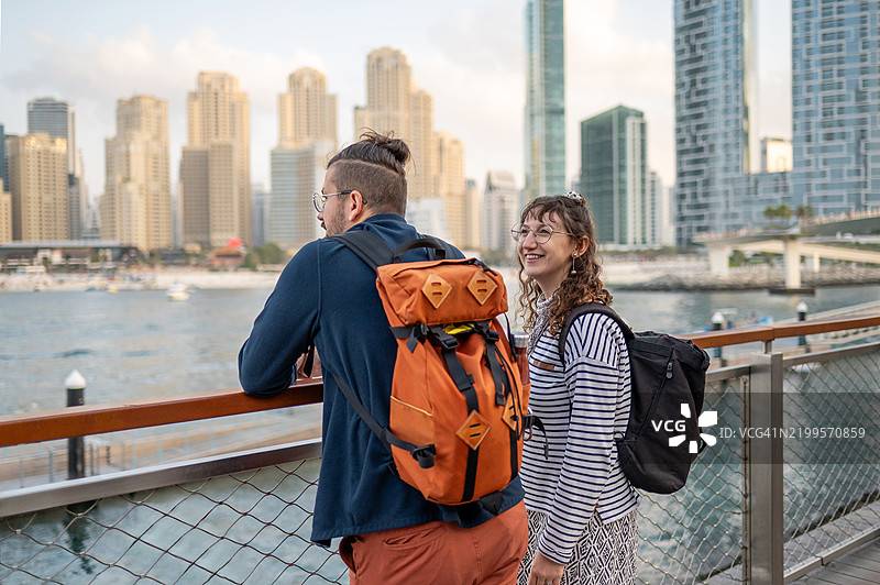 一对情侣在迪拜码头享受水边美景，背后是摩天大楼。图片素材