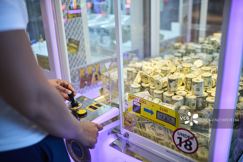 男人在玩装满现金的抓娃娃机图片素材