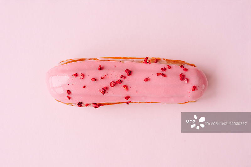 美味的覆盆子泡芙，上面覆盖着粉色糖霜，并撒上冻干覆盆子，背景为柔和的粉色，营造出甜美而简约的美感。图片素材