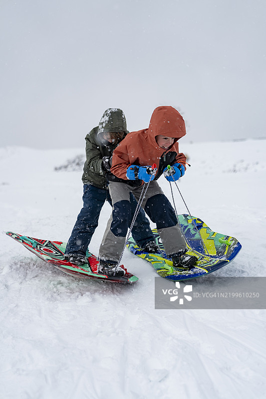 两个兄弟在雪橇上滑雪图片素材