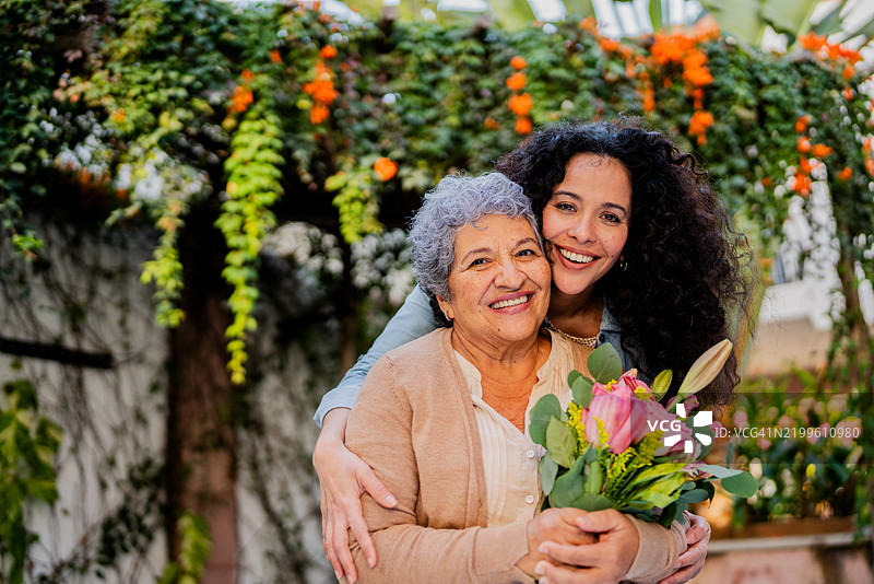中年女性在户外拥抱并送花给母亲的肖像图片素材