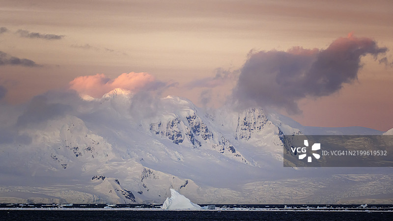 美丽的冰山在南极日出时映衬着粉色云彩图片素材