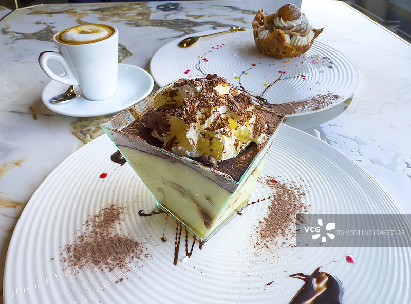 意大利餐厅中优雅装饰盘上的美丽甜点提拉米苏、米粉和卡布奇诺咖啡图片素材