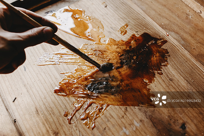 一只手正在用画笔在木质表面涂抹清漆图片素材