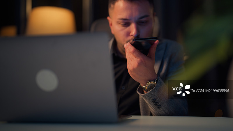 商人深夜在笔记本电脑上工作，使用人工智能应用程序为他的财务业务寻求帮助图片素材