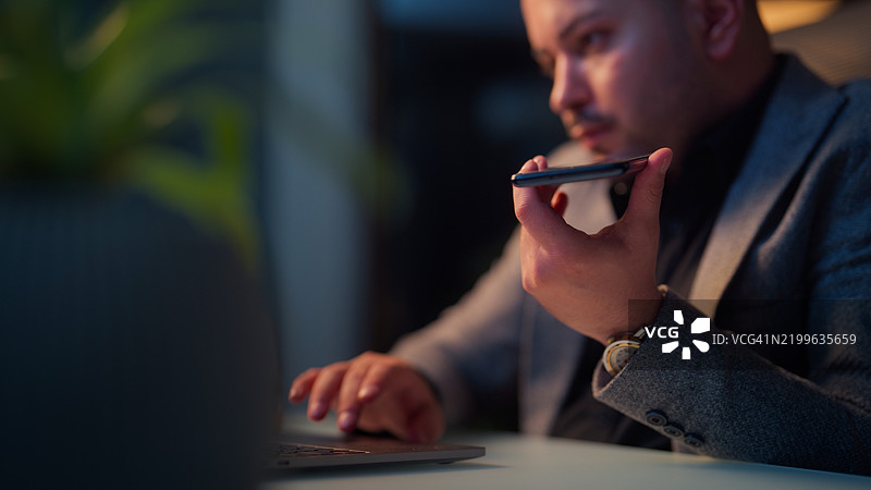 商人深夜在笔记本电脑上工作，使用人工智能应用程序为他的财务业务寻求帮助图片素材