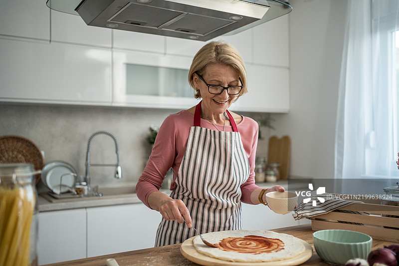 成熟的女性在厨房制作自制披萨图片素材