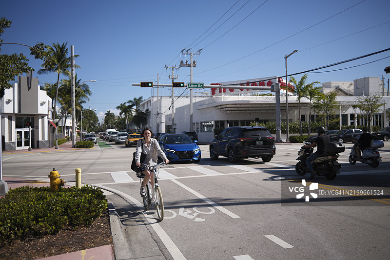 迈阿密，佛罗里达州，美国的城市街景，骑自行车的人、汽车和棕榈树在晴朗的蓝天下。图片素材