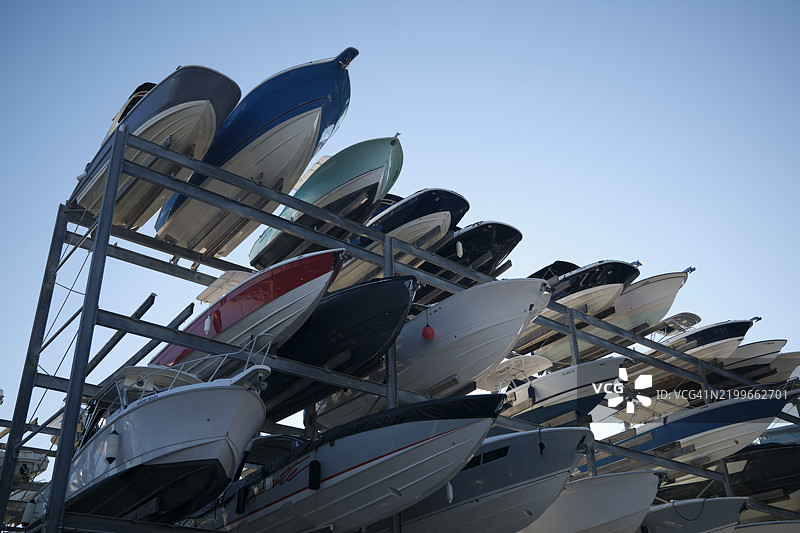 一排五颜六色的摩托艇整齐地堆放在金属储存结构中，蓝天清澈，位于美国佛罗里达州迈阿密。图片素材