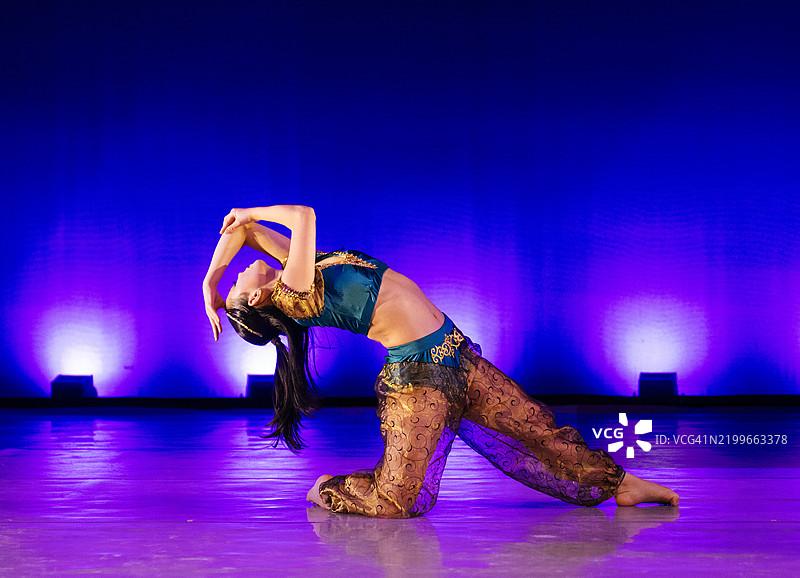 穿着色彩斑斓服装的舞者在舞台上表演，背景是生动的蓝色和紫色灯光。《胡桃夹子》，美国贝恩布里奇岛图片素材
