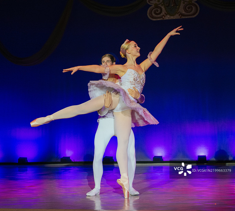 芭蕾舞者穿着优雅的服装在舞台上表演，背景灯光绚丽。《胡桃夹子》，美国贝恩布里奇岛图片素材