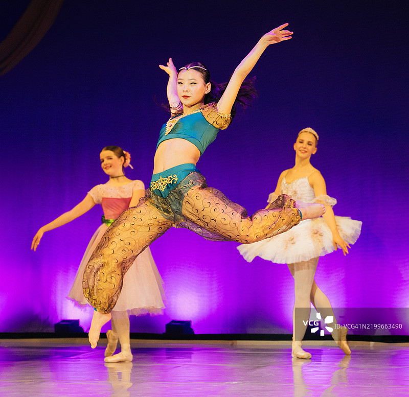 舞者们在舞台上穿着色彩斑斓的服装，背景是生动的紫色幕布。《胡桃夹子》，美国贝恩布里奇岛图片素材