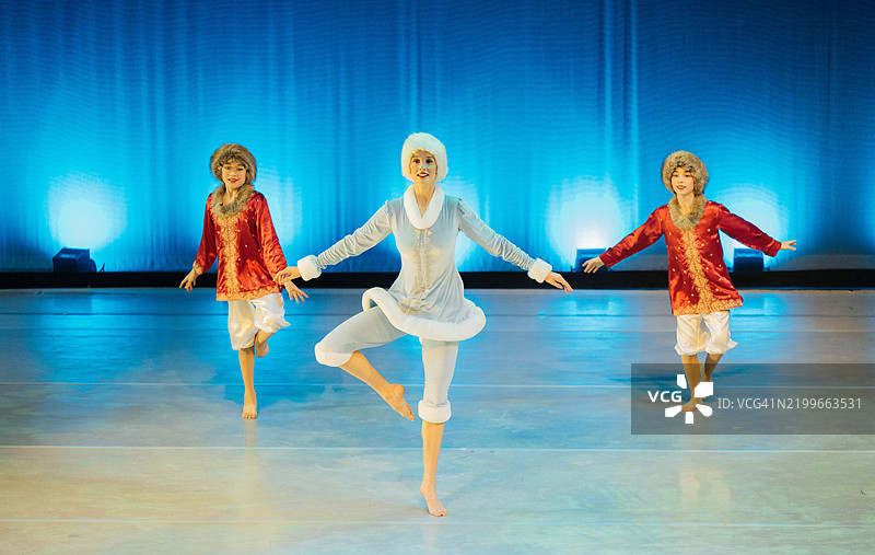 三位穿着色彩斑斓服装的芭蕾舞者在明亮的舞台上表演。《胡桃夹子》，美国贝恩布里奇岛图片素材