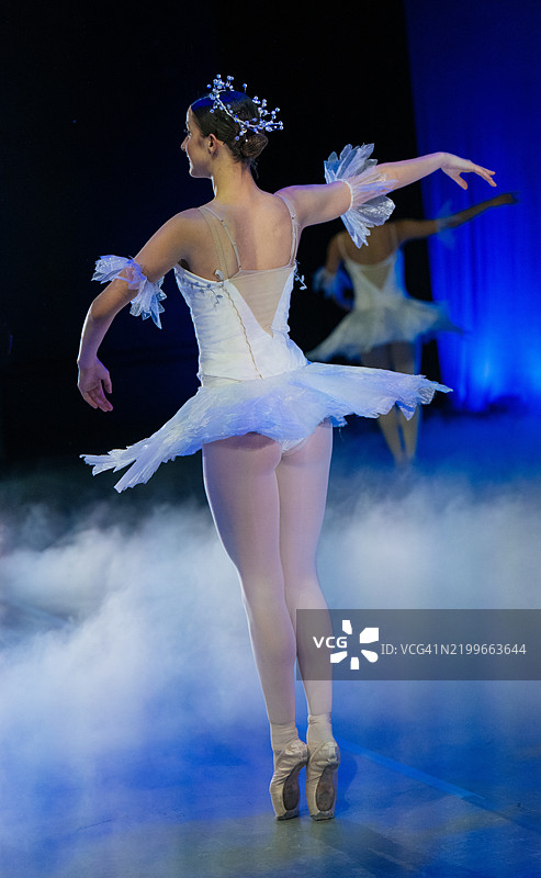 穿着白色芭蕾舞裙和尖头鞋的芭蕾舞者在朦胧的舞台上优雅地舞蹈。《胡桃夹子》，美国贝恩布里奇岛图片素材