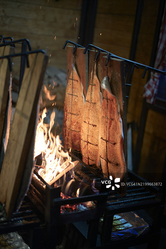 在圣诞市场上，调味鱼片在明火上烹饪，旁边有木质支架。图片素材