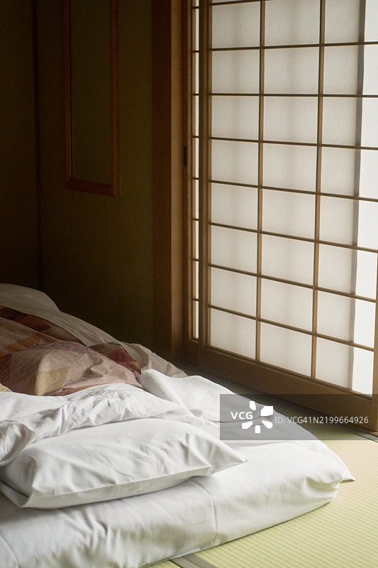 阳光透过纸屏风洒在整齐铺好的日本榻榻米床垫上，背景是日本阿尔卑斯山，柴场温泉。图片素材