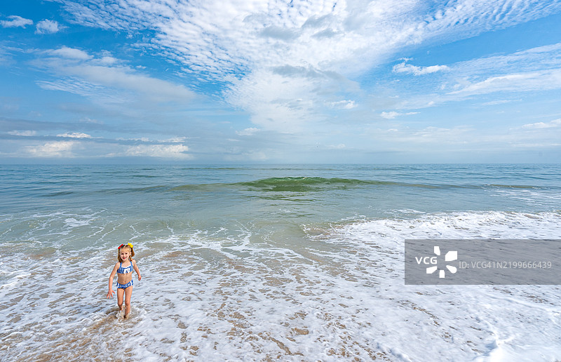年轻女孩在佛罗里达州梅里特岛的卡纳维拉尔国家海岸沿大西洋的海滩上早晨玩耍图片素材