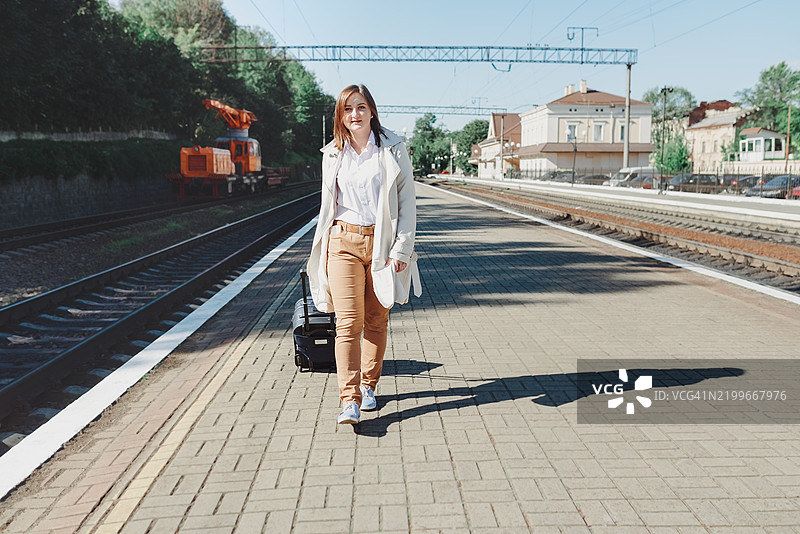年轻女子在乌克兰利沃夫的火车站站台上推着行李箱走过图片素材