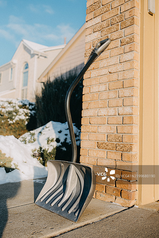一把雪铲靠在砖墙上图片素材