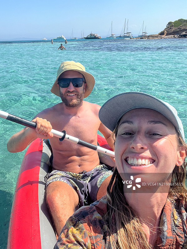 微笑的情侣在清澈的蓝色水域划皮艇图片素材