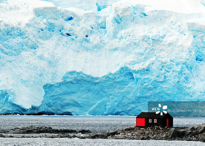 阿根廷避难小屋位于水边，周围有帝企鹅和大型冰川，位于南极的佩特曼岛。图片素材