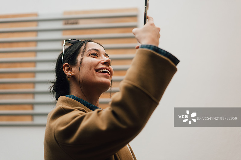 年轻女性用智能手机自拍并微笑图片素材