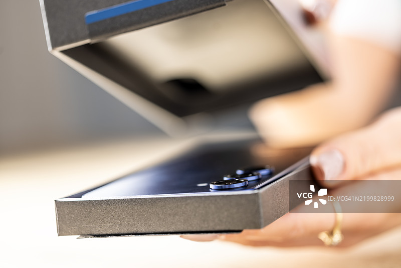 一个人手持新智能手机的盒子或保护壳并进行拆包。特写镜头。图片素材